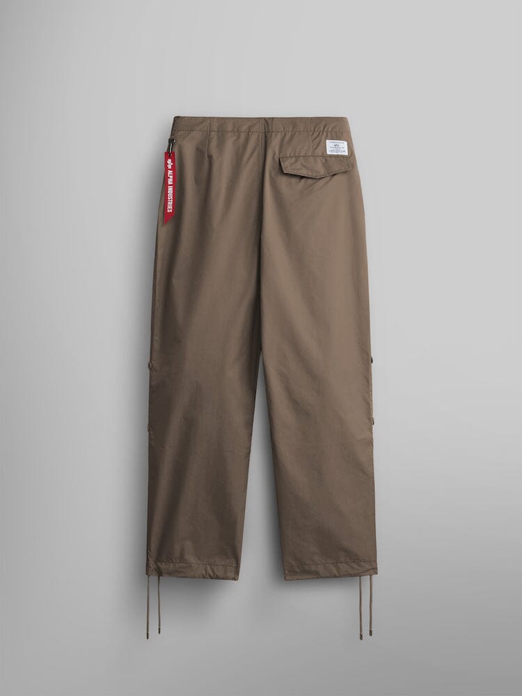 Alpha Industries Lightweight Parachute Pant in khaki nylon/cotton blend with elastic waistband, single back pocket, red tag accent, and adjustable drawstring cuffs.