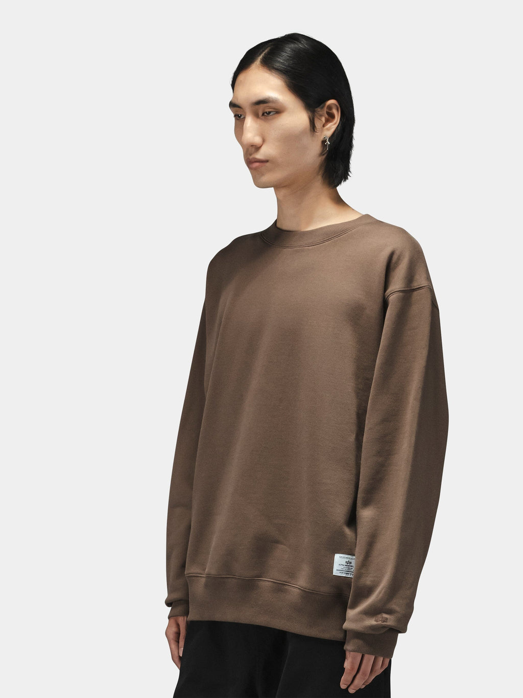 Alpha Industries Patched Crewneck in cotton-poly, loose fit, military-inspired design with patches; paired with black pants.