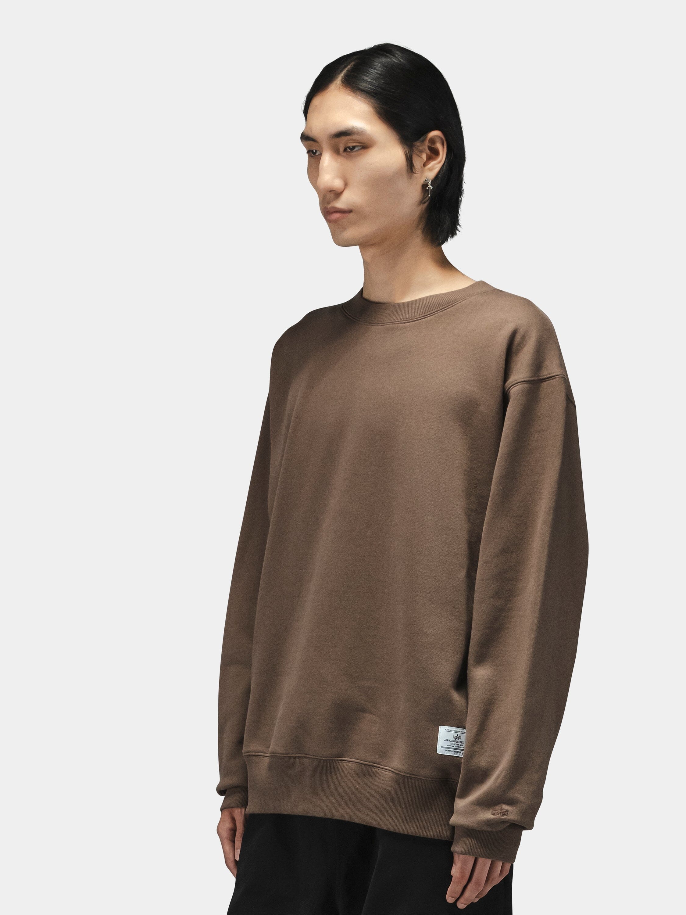 Alpha Industries Patched Crewneck in cotton-poly, loose fit, military-inspired design with patches; paired with black pants.