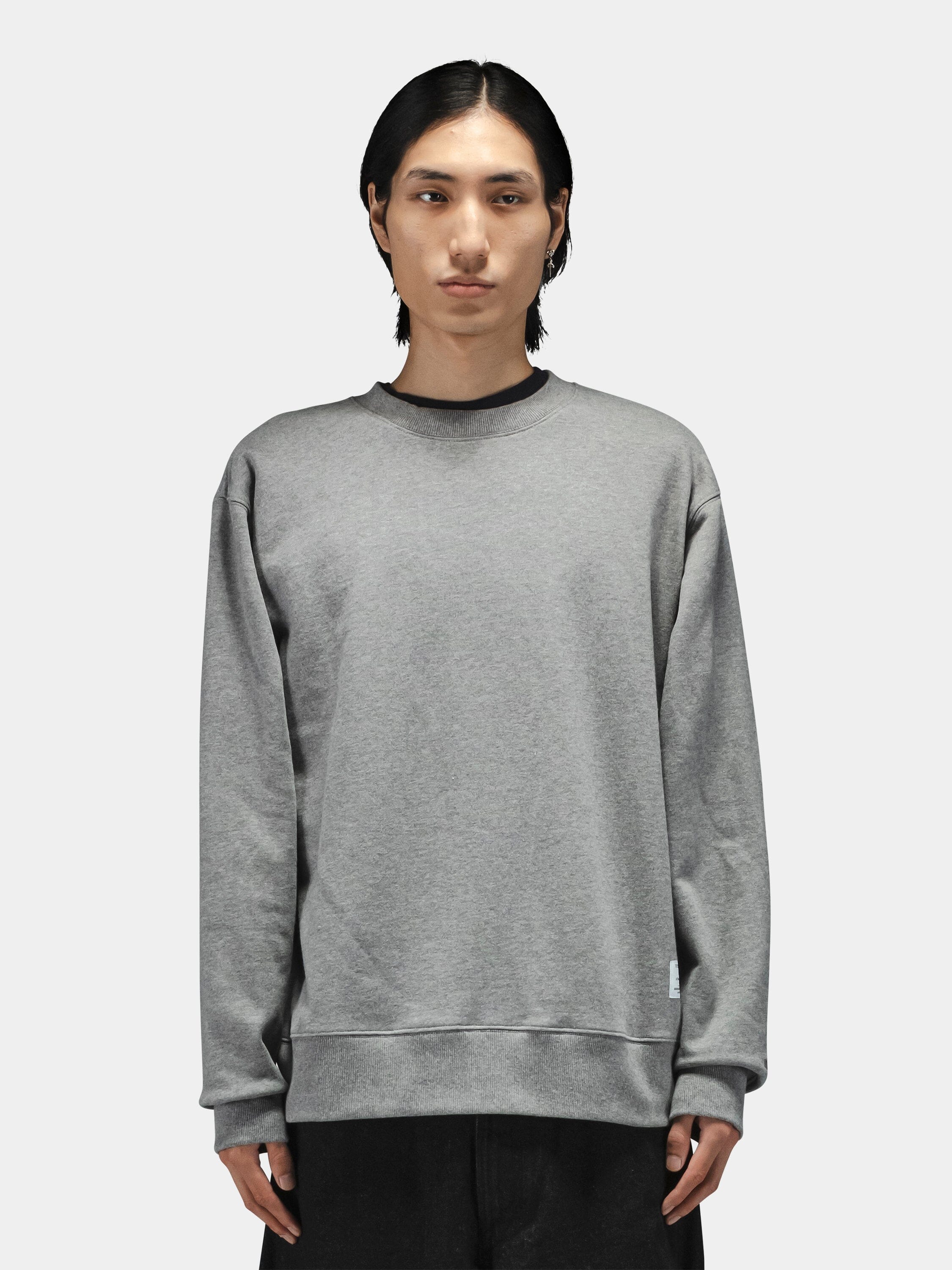 Alpha Industries Patched Crewneck sweatshirt in black with military-inspired patches, paired with black pants.
