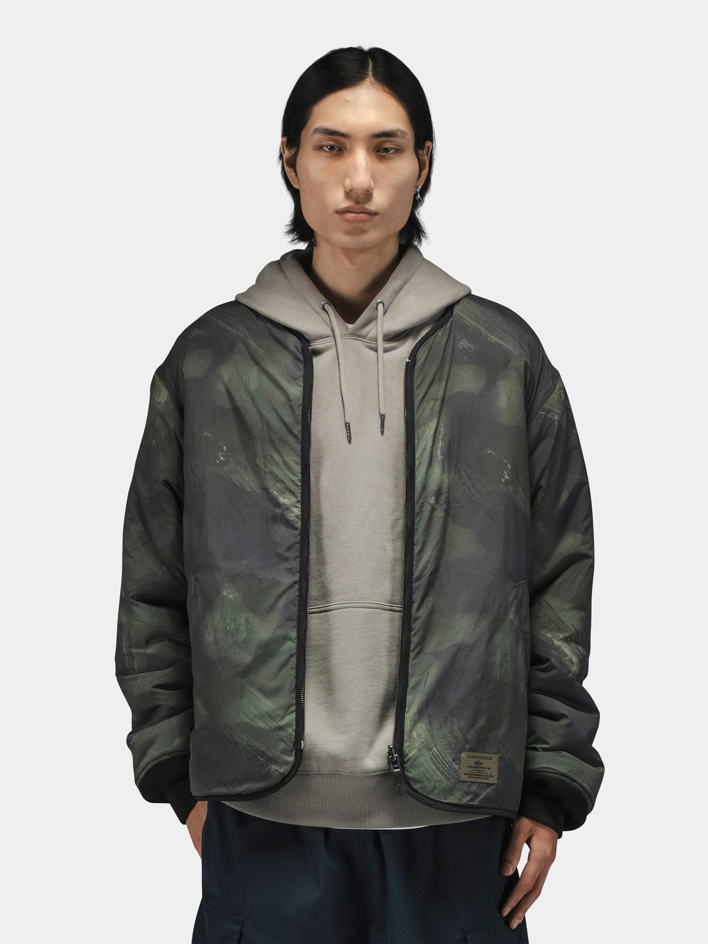 Alpha Industries Reversible M-65 Quilted Liner under a camo jacket; quilted texture, reversible design.