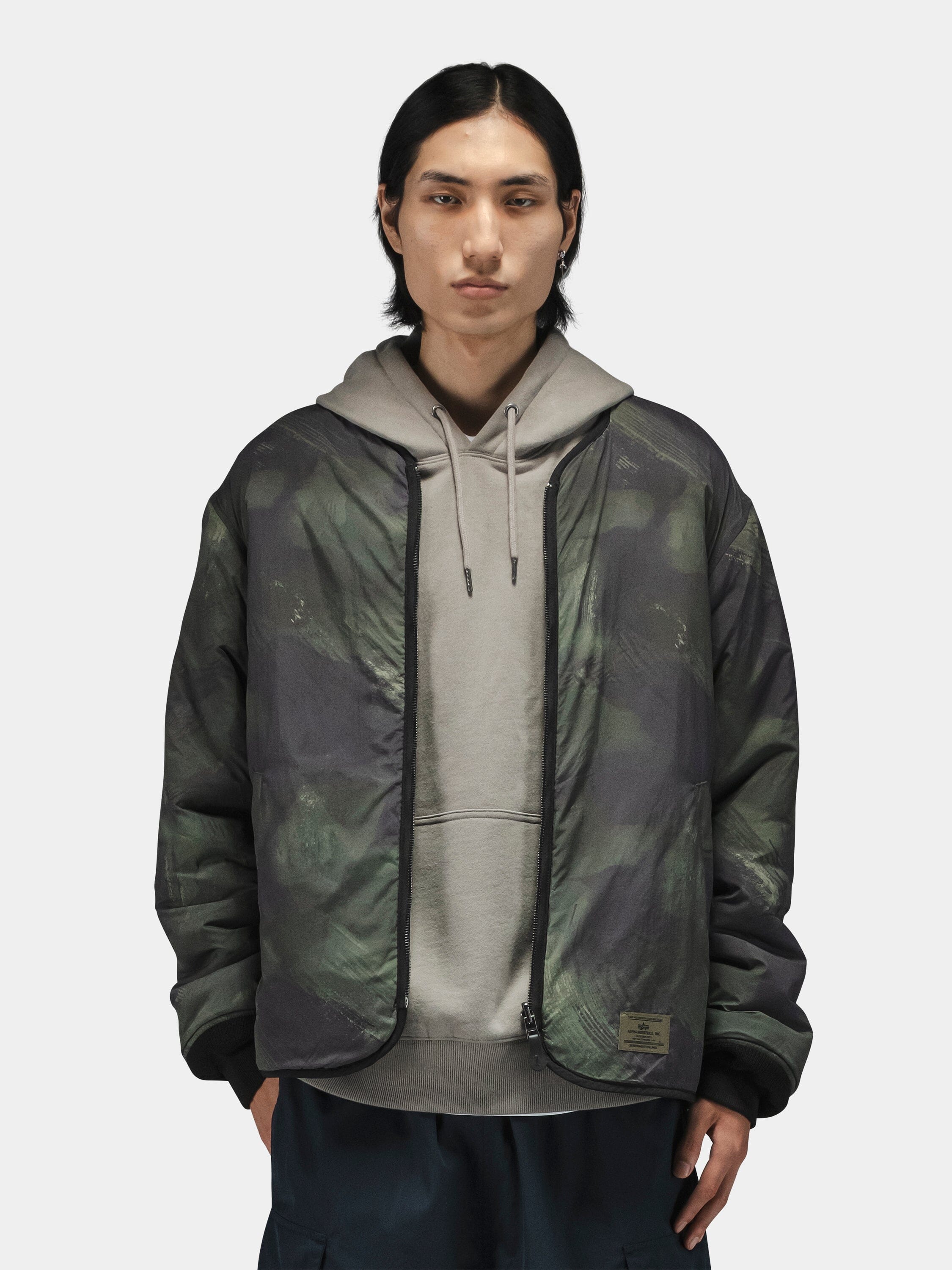 Alpha Industries Reversible M-65 Quilted Liner under a camo jacket; quilted texture, reversible design.