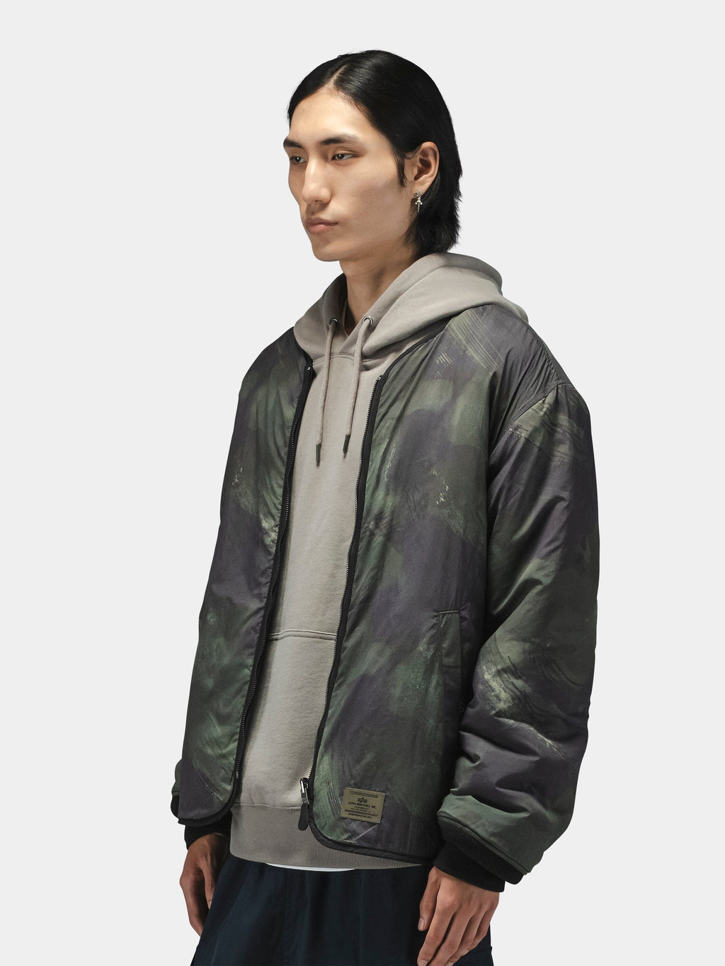 Alpha Industries Reversible M-65 Quilted Liner camo jacket over gray hoodie; quilted design, camouflage pattern.