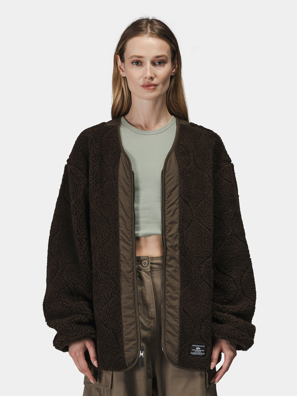 Alpha Industries Reversible M-65 Quilted Liner in dark brown with light green crop top and khaki pants.