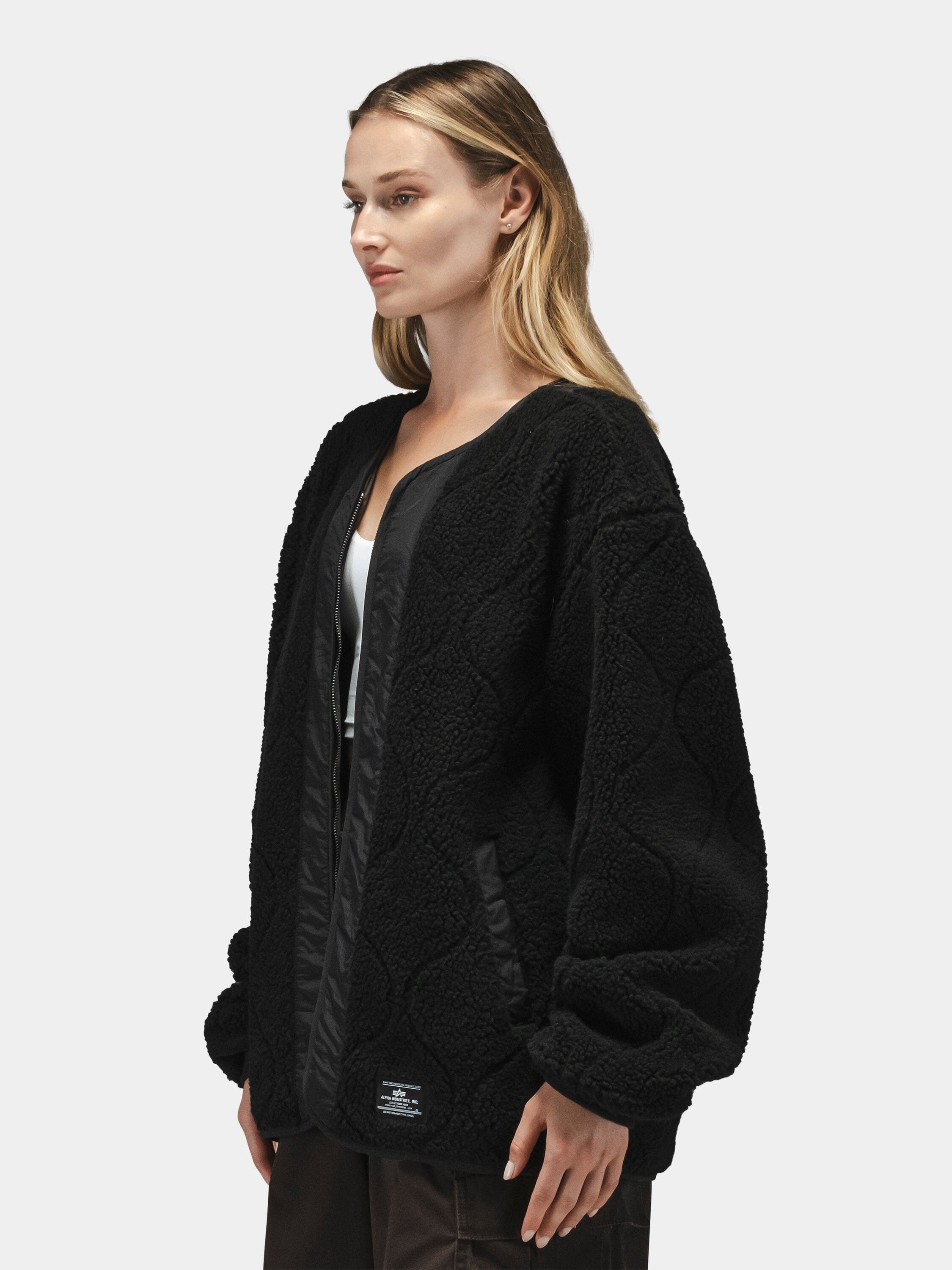Alpha Industries Reversible M-65 Quilted Liner, black, loose fit, quilted design, worn over a white top.