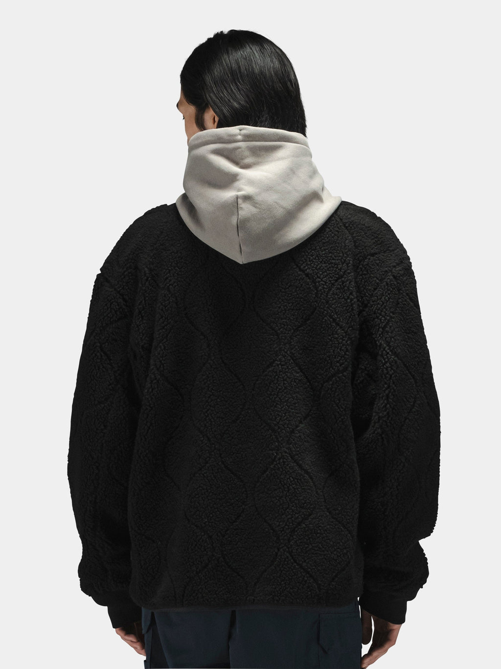 Alpha Industries Reversible M-65 Quilted Liner in black, worn over a gray hooded sweatshirt.