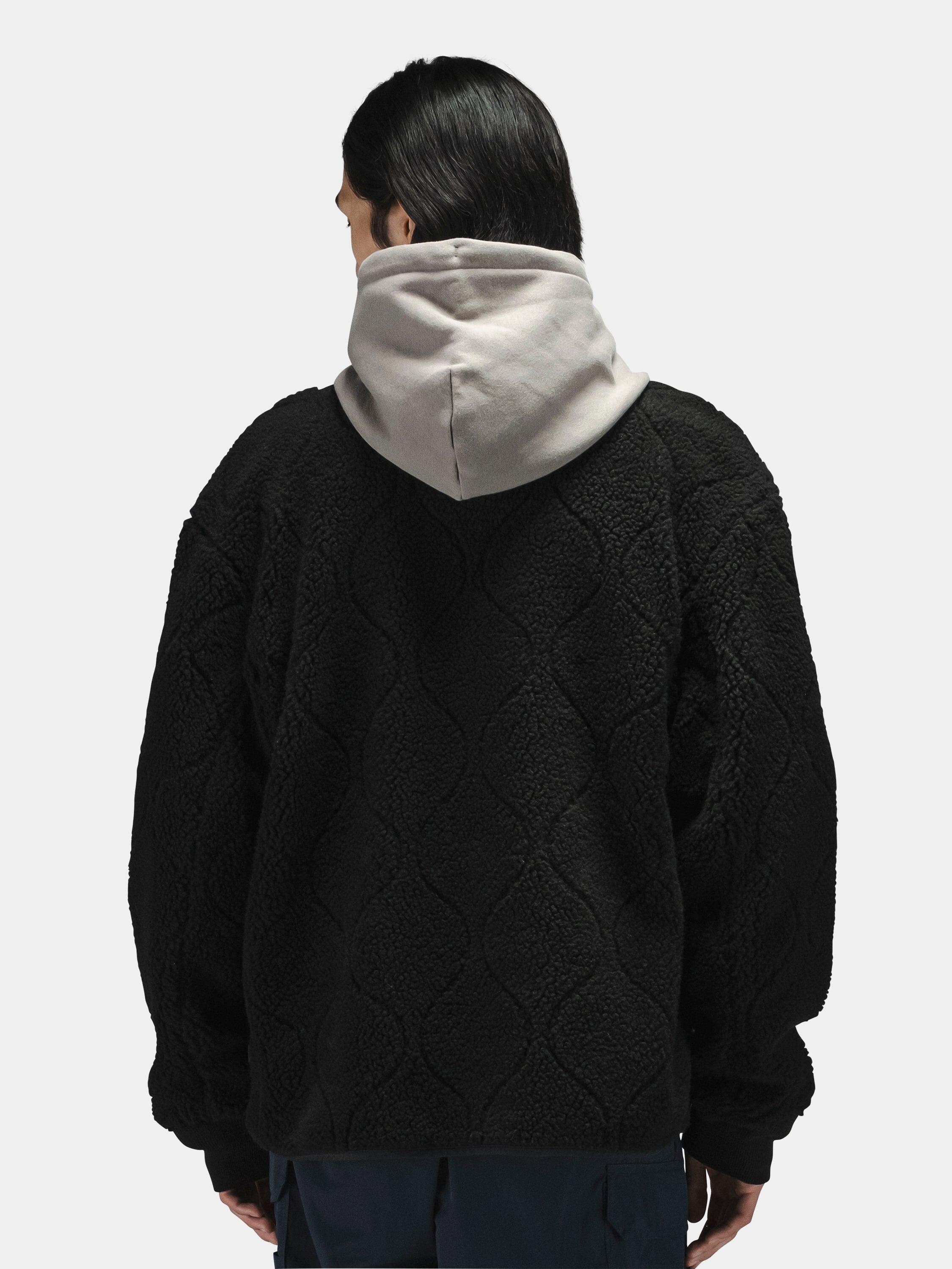 Alpha Industries Reversible M-65 Quilted Liner in black, worn over a gray hooded sweatshirt.