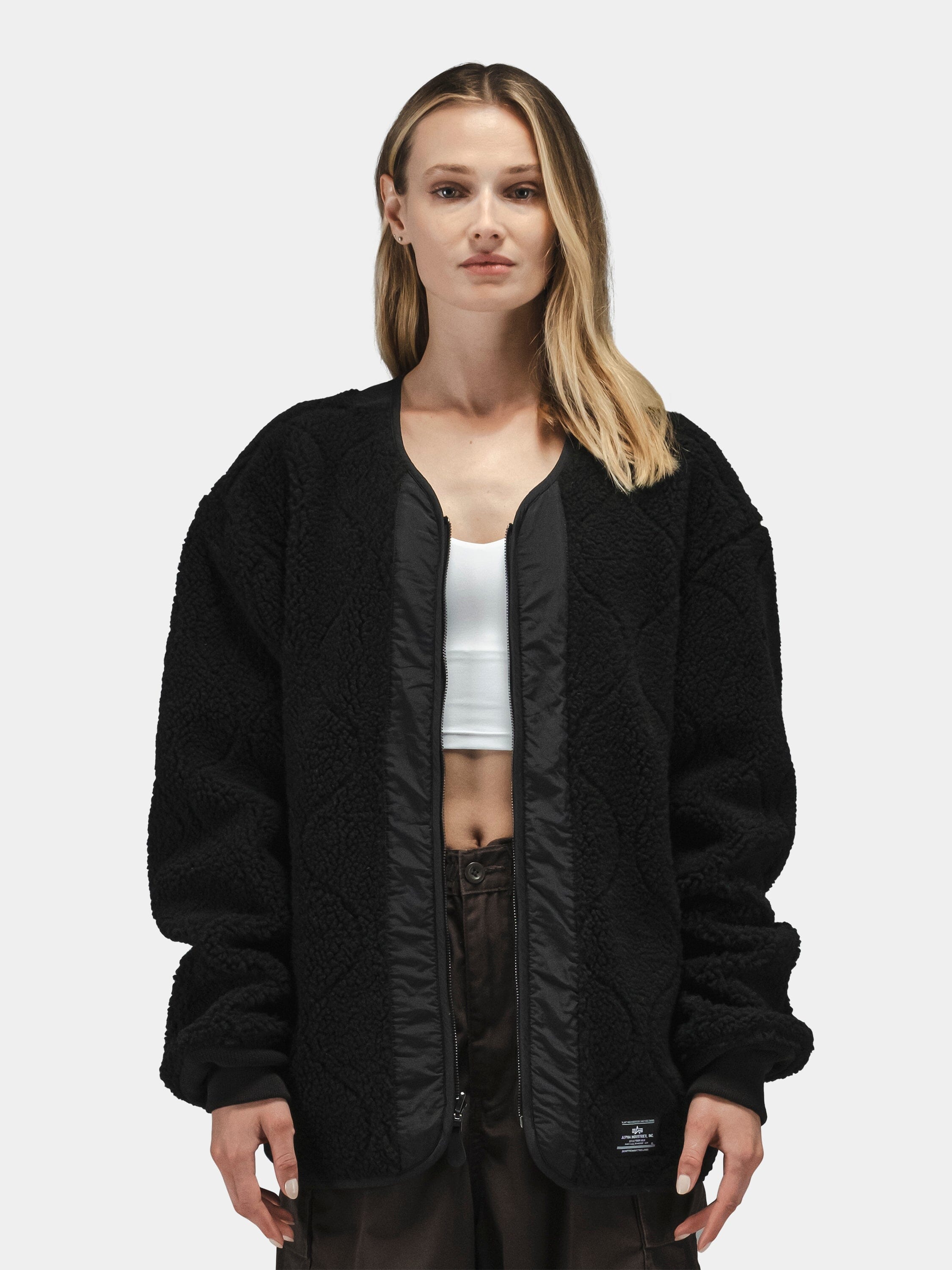 Alpha Industries Reversible M-65 Quilted Liner jacket with quilted material and layered design. White crop top, dark pants.