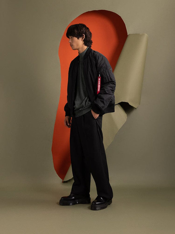 Full body side view of a person wearing the black Reversible Onion Quilted MA-1 Bomber Jacket by Alpha Industries.
