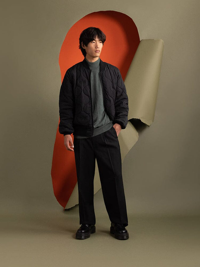 Full body view of a person wearing the black Reversible Onion Quilted MA-1 Bomber Jacket in reversible view by Alpha Industries.