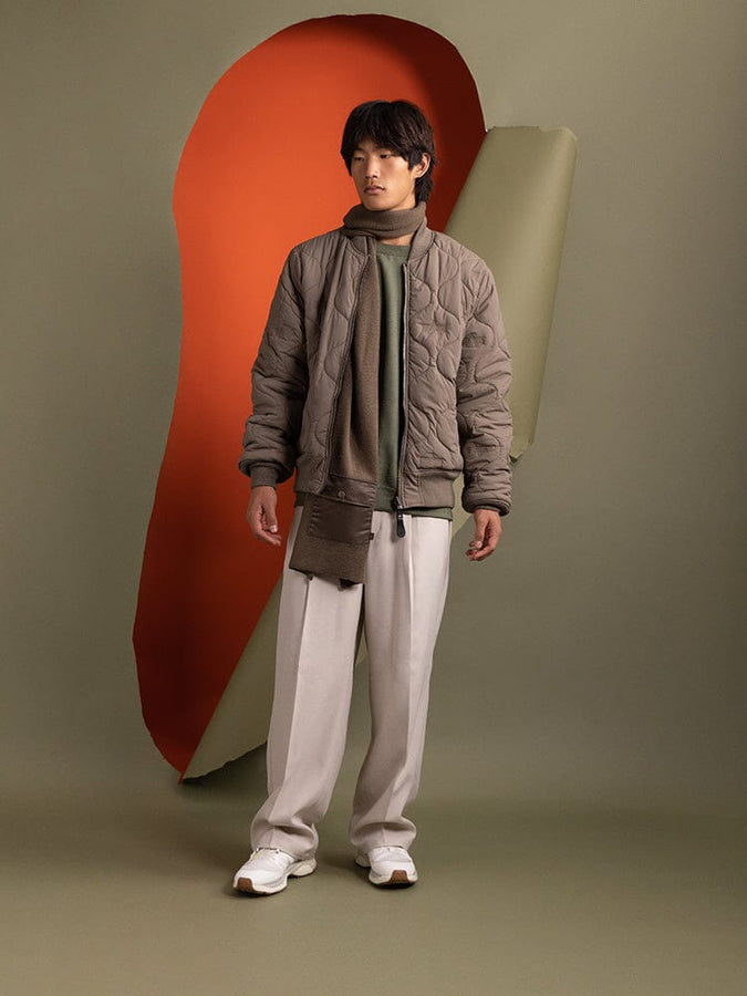 Full body view of person is dressed in an Alpha Industries Reversible Onion Quilted MA-1 Bomber Jacket in green.