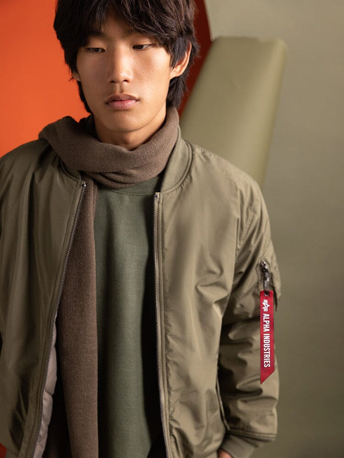 Close up of a person wearing a Reversible Onion Quilted MA-1 Bomber Jacket in green by Alpha Industries.