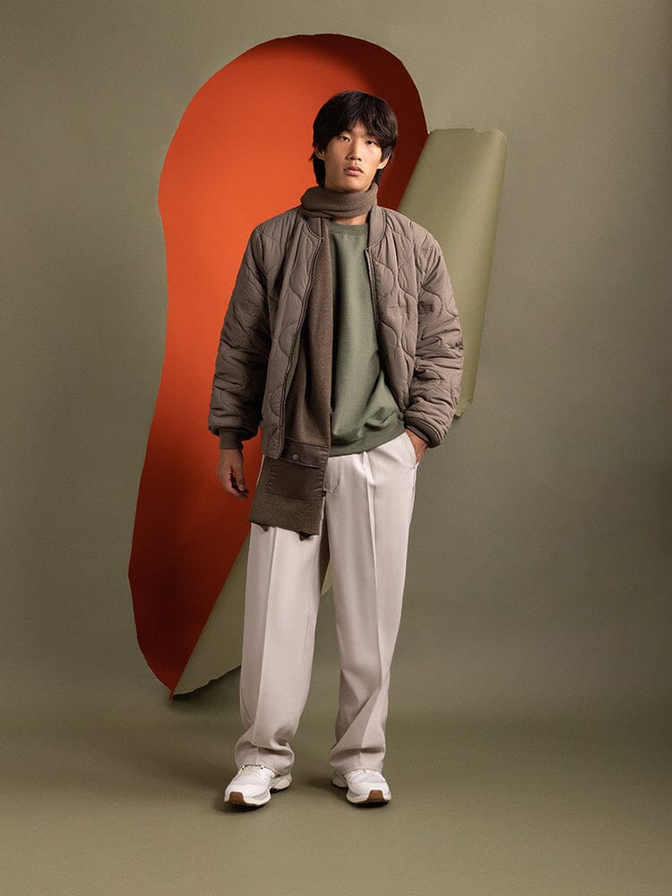 Full body view of a person wearing the reversible side of the Reversible Onion Quilted MA-1 Bomber Jacket in green by Alpha Industries.