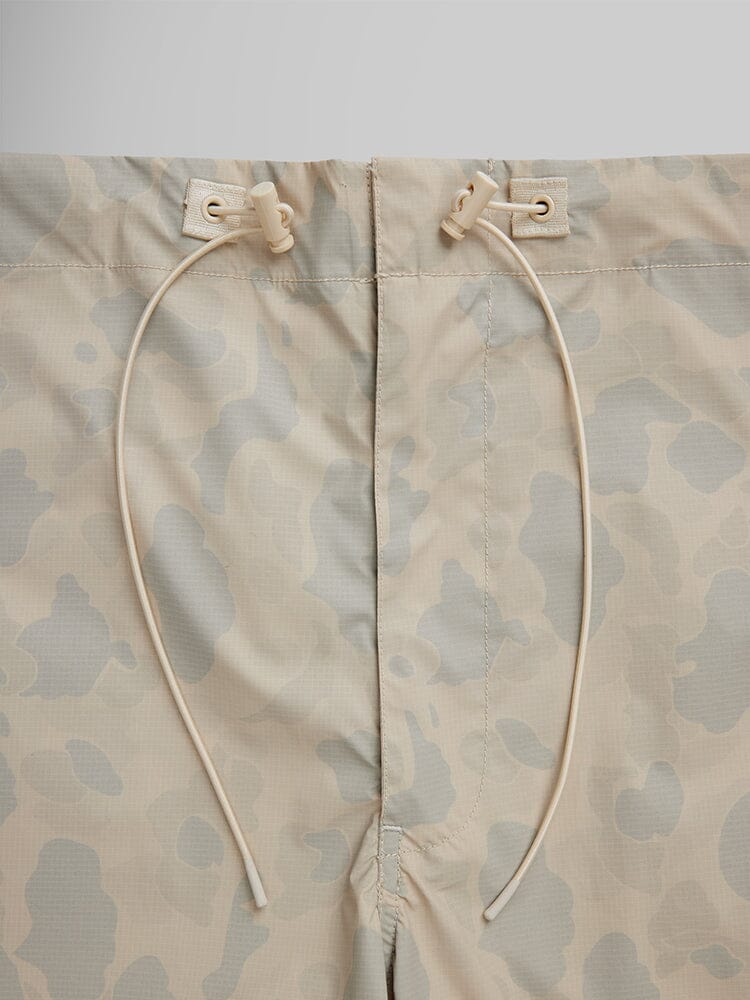 Alpha Industries Lightweight Parachute Pant Frogskin in beige frogskin camo with two drawstrings and plastic toggles at the waistband.