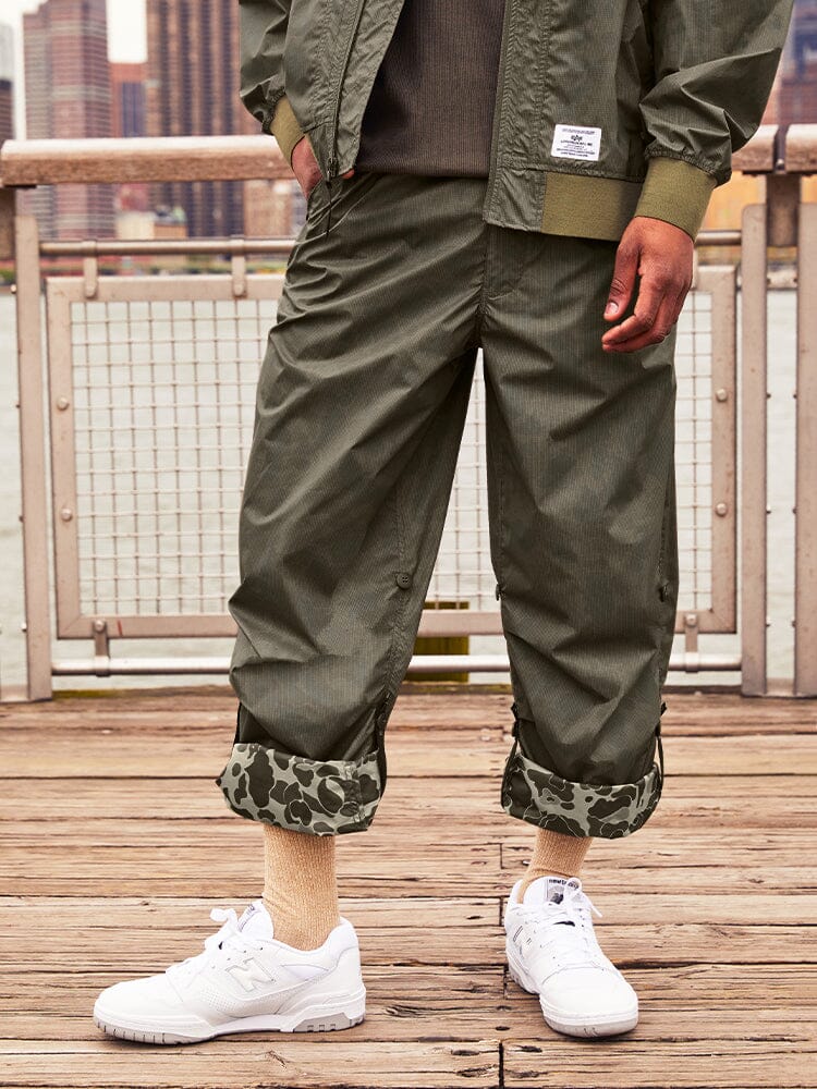 Alpha Industries Lightweight Parachute Pant Frogskin, white sneakers, beige socks, green jacket.