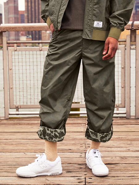 Alpha Industries Lightweight Parachute Pant Frogskin, white sneakers, beige socks, green jacket.