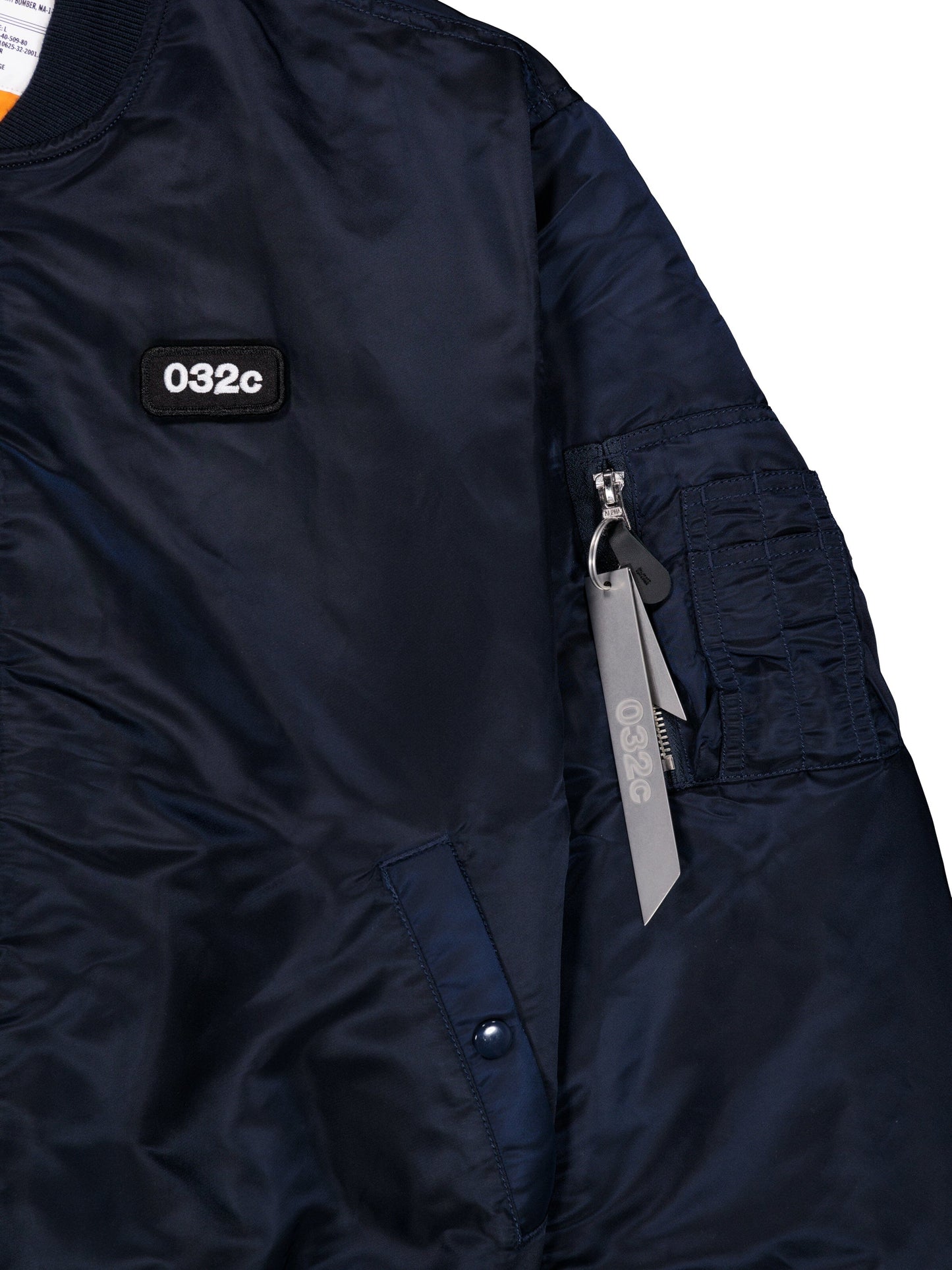 Alpha X 032c Flight Bomber by Alpha Industries in navy flight nylon with 032c chest patch and zippered sleeve pocket with gray 032c tag.