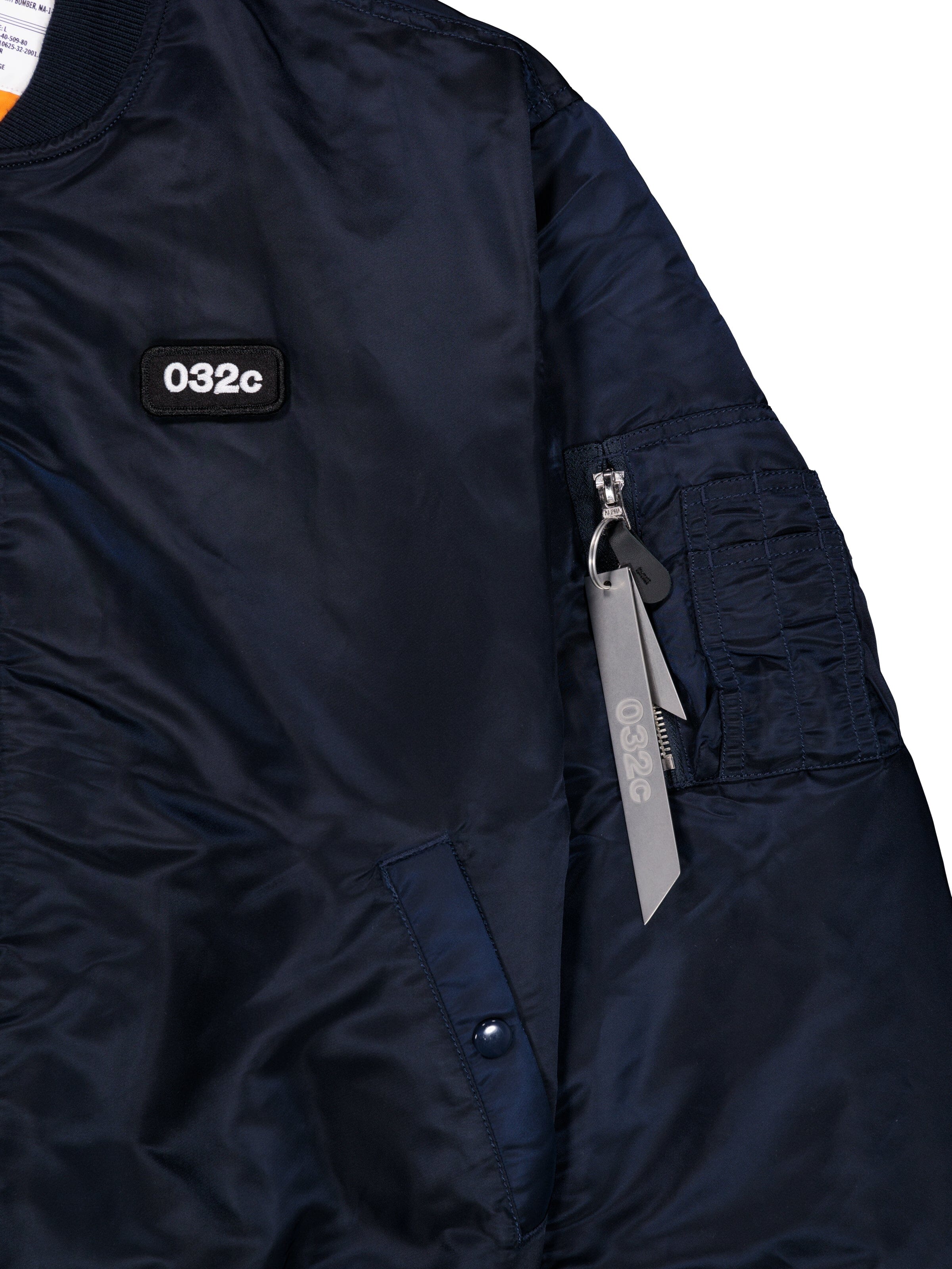 Alpha X 032c Flight Bomber by Alpha Industries in navy flight nylon with 032c chest patch and zippered sleeve pocket with gray 032c tag.