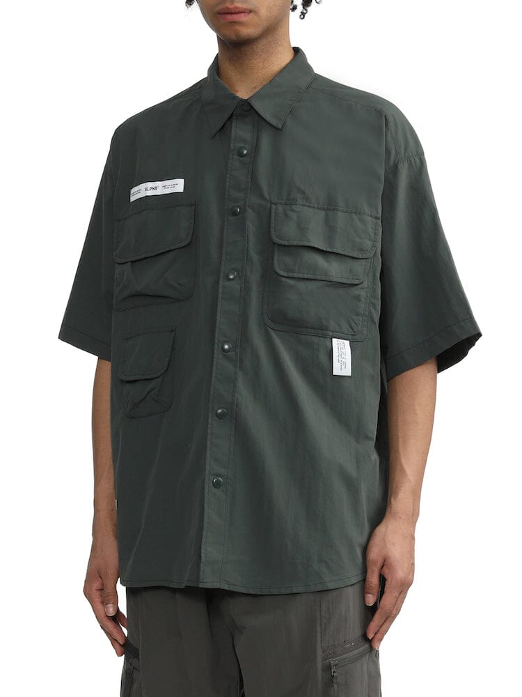 Unfrm Nylon Utility Shirt by Alpha Industries, short-sleeve dark green nylon button-up with multiple patch pockets and small white labels.