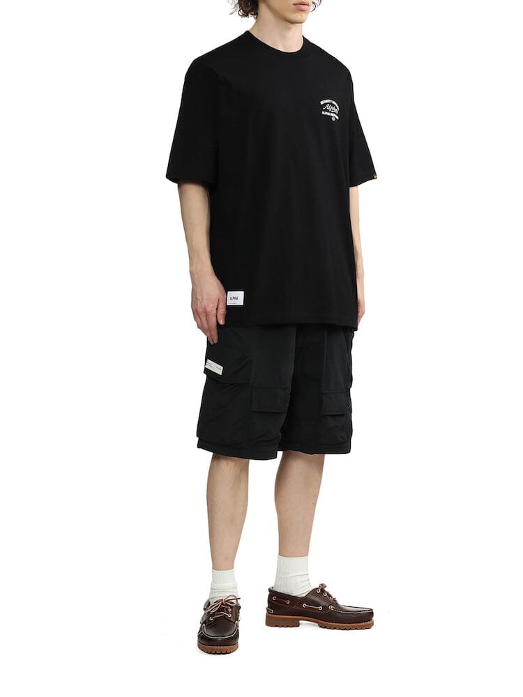 Alpha Industries Unfrm Nylon Utility Short, Black Oversized T-Shirt, White Socks, Brown Boat Shoes.