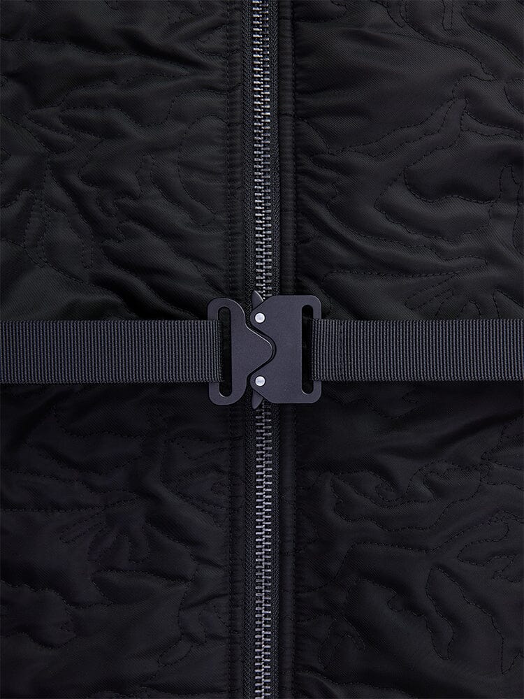 Close-up view of the Women’s Camo Quilted Belted MA-1 Bomber Jacket by Alpha Industries, featuring black quilted fabric, complete with a zipper and black buckle strap across the center.