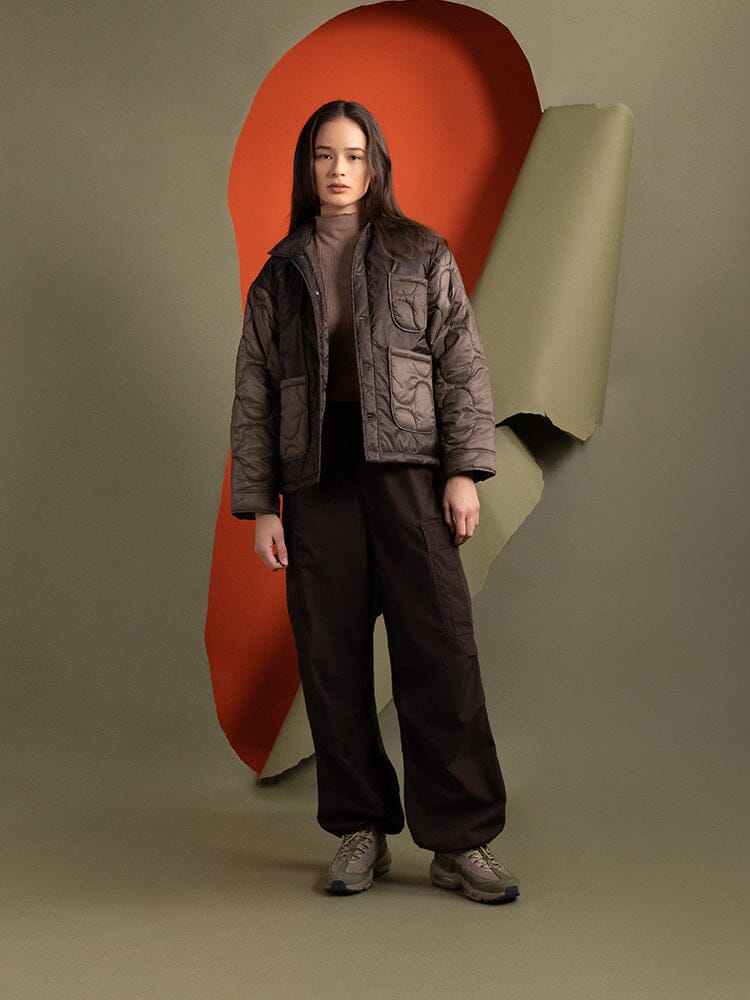 Full body view of a person wearing Alpha Industries' Women's Insulated Chore Coat in chocolate, featuring chic onion quilting.