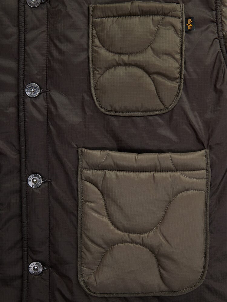 Close-up of the Alpha Industries women's insulated chore coat in a chocolate hue, featuring quilted onion stitching, varying-sized front pockets, and button closures.