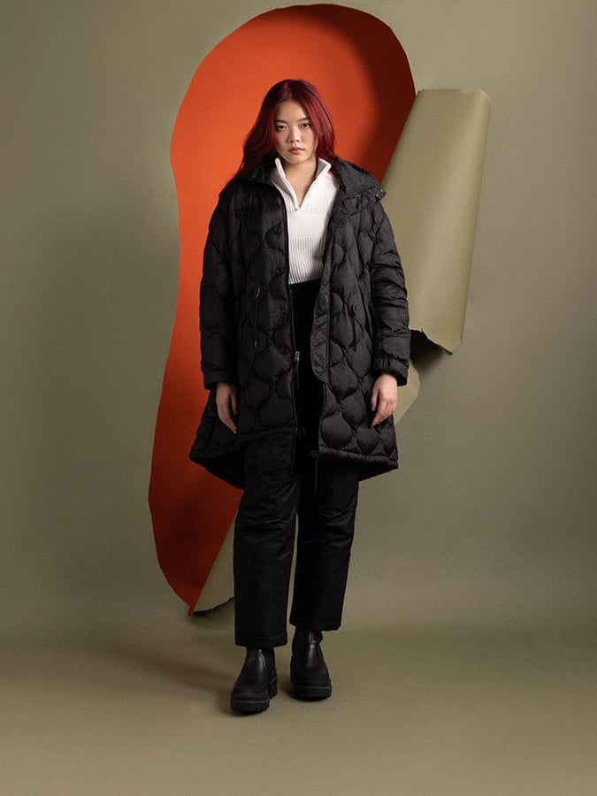 A person wears the water-resistant Women's M-65 Fishtail Puffer in black from Alpha Industries.