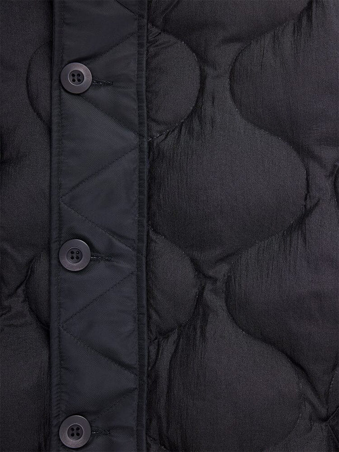 Close-up of the Women's M-65 Fishtail Puffer by Alpha Industries, featuring a black quilted fabric with water-resistant properties, four round black buttons, and a diamond-patterned stitch design reminiscent of onion quilting.