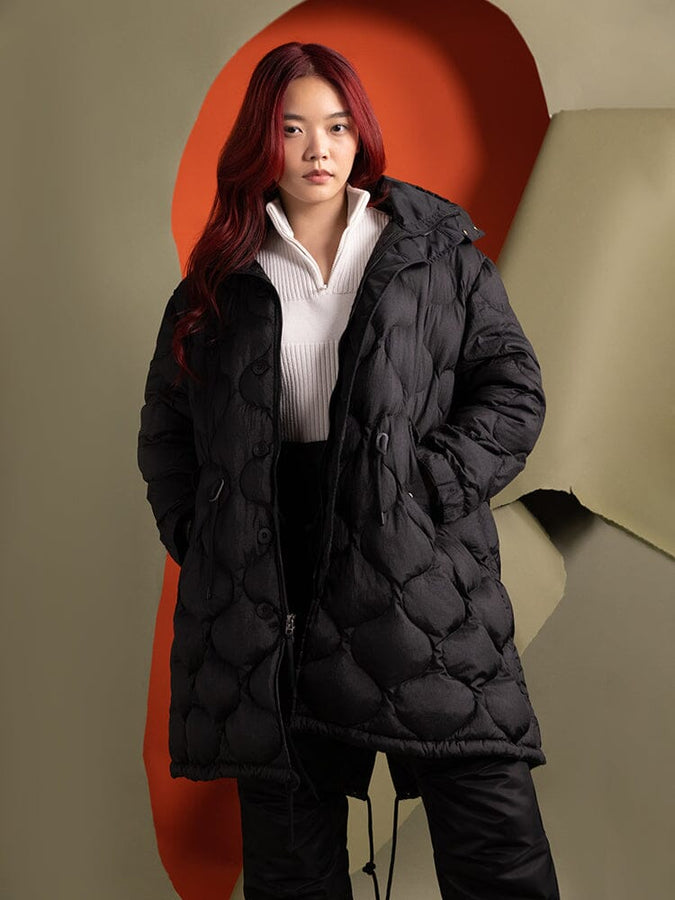 A person  wearing the Women's M-65 Fishtail Puffer in black by Alpha Industries, paired with a white top.