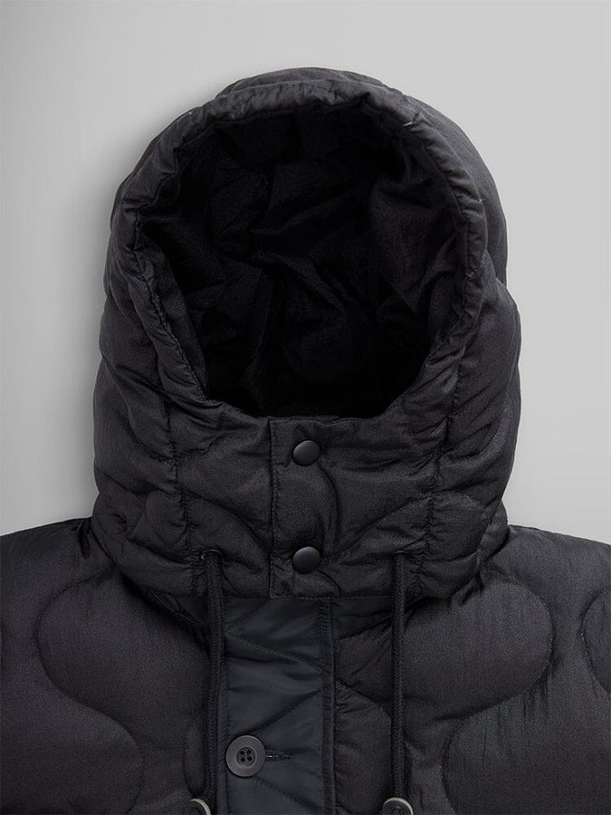 Close-up of the Women's M-65 Fishtail Puffer in black by Alpha Industries, showcasing onion quilting along with button and drawstring accents on the front.