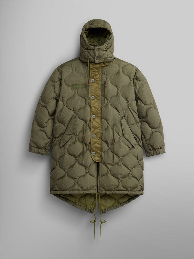 The Women's M-65 Fishtail Puffer by Alpha Industries in OG-107 Green, featuring a water-resistant fabric with onion quilting, a hood, button and zipper closure, an asymmetric hem, and adjustable drawstrings at the waist and hem.