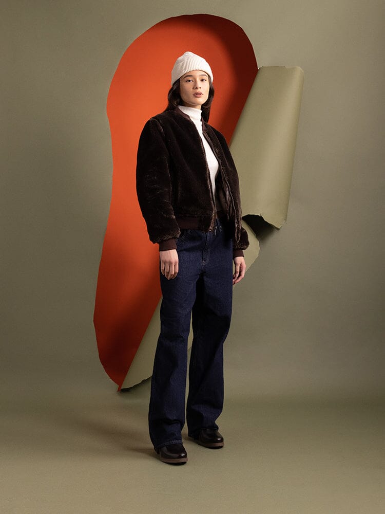 Side-view of a person wearing the reversible side of the Women's Reversible Faux Leather MA-1 Bomber Jacket in brown chocolate by Alpha Industries.