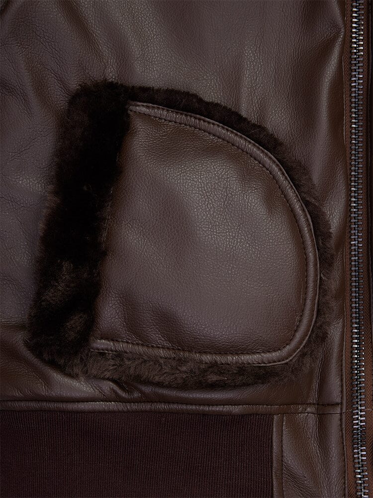 Close-up of the Women's Reversible Faux Leather MA-1 Bomber Jacket by Alpha Industries, featuring a brown faux leather material with a zipped pocket and dark shearling lining.