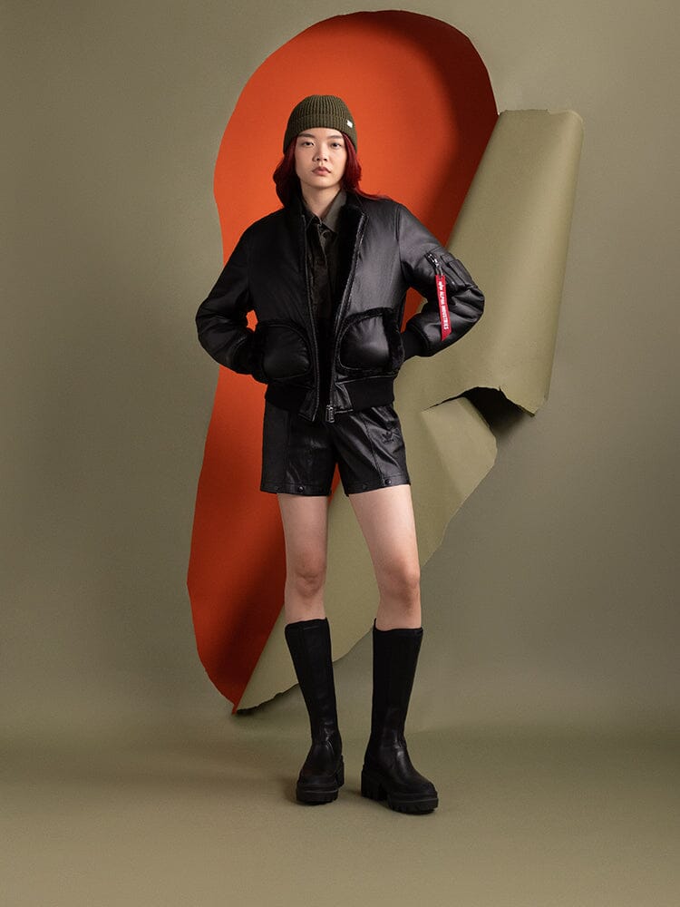 Full body view of a person wearing the Women's Reversible Faux Leather MA-1 Bomber Jacket in black by Alpha Industries.