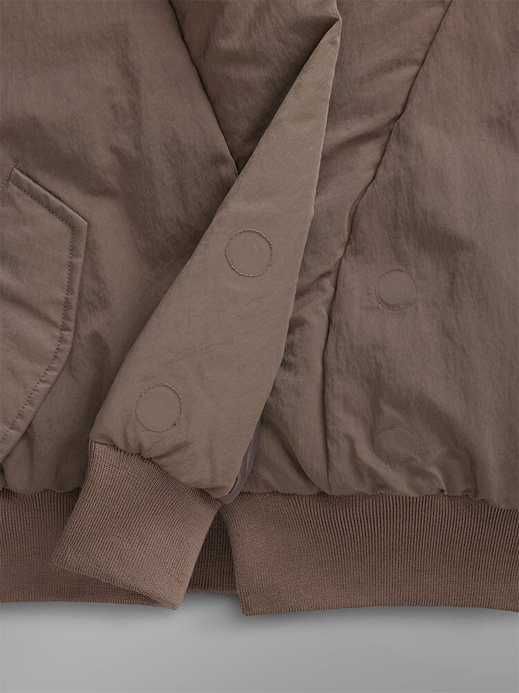 Close-up of the Women's Shawl Collar Bomber Jacket by Alpha Industries, showcasing a brown quilted design with detailed pockets, buttons, and ribbed cuffs.