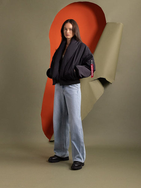 Full body view of a person standing to the side wearing the Women's Shawl Collar Bomber Jacket in black by Alpha Industries.