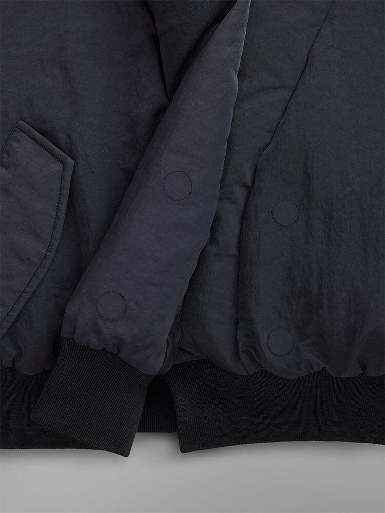 Close-up of the Women's Shawl Collar Bomber Jacket in a dark shade, showcasing its padded design with visible stitching and pocket detail. The sleeves and hem are accented with black ribbed cuffs.