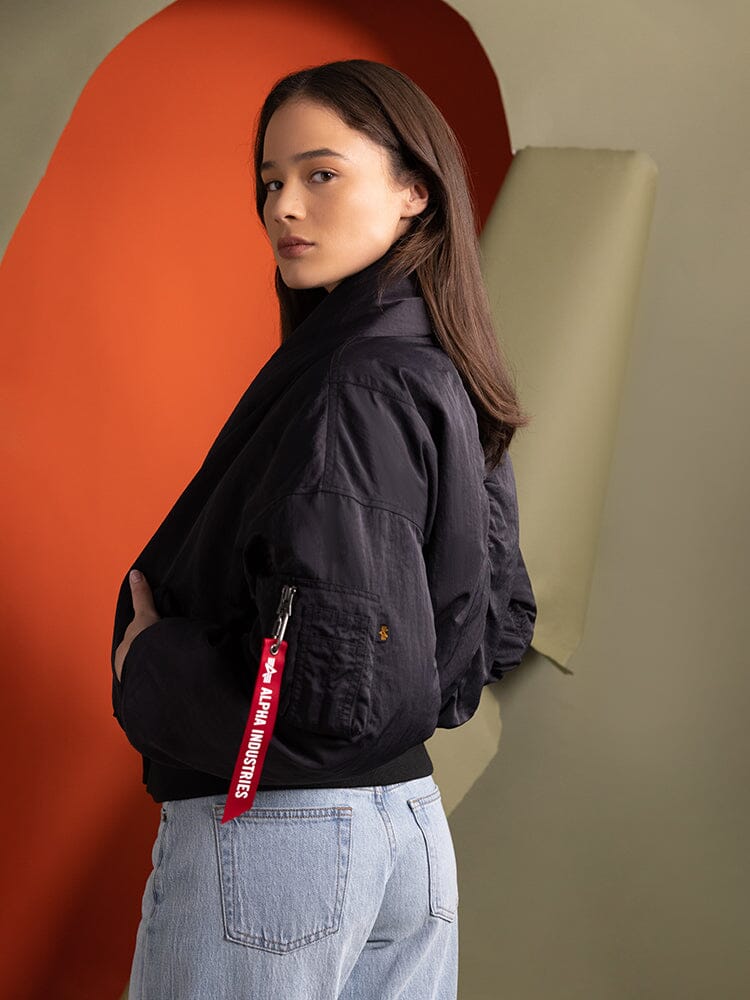 Side-view of a person wearing the Women's Shawl Collar Bomber Jacket in black by Alpha Industries.
