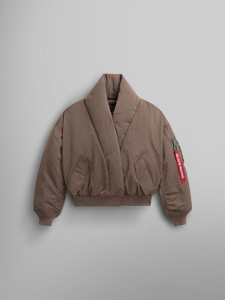 The Women's Shawl Collar Bomber Jacket by Alpha Industries in Coyote Brown features down-filled warmth, a shawl collar, and ribbed cuffs and hem. It is accented with a red tag on the sleeve.
