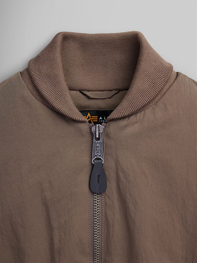 Close-up of the Women's Short Cinched Waist Jacket by Alpha Industries, showcasing a thick collar and welt pocket with a zipper.