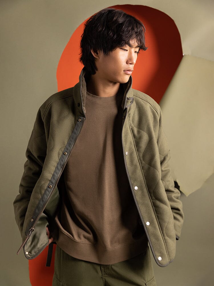 A person wearing the Wool Deck Jacket  in green by Alpha Industries.