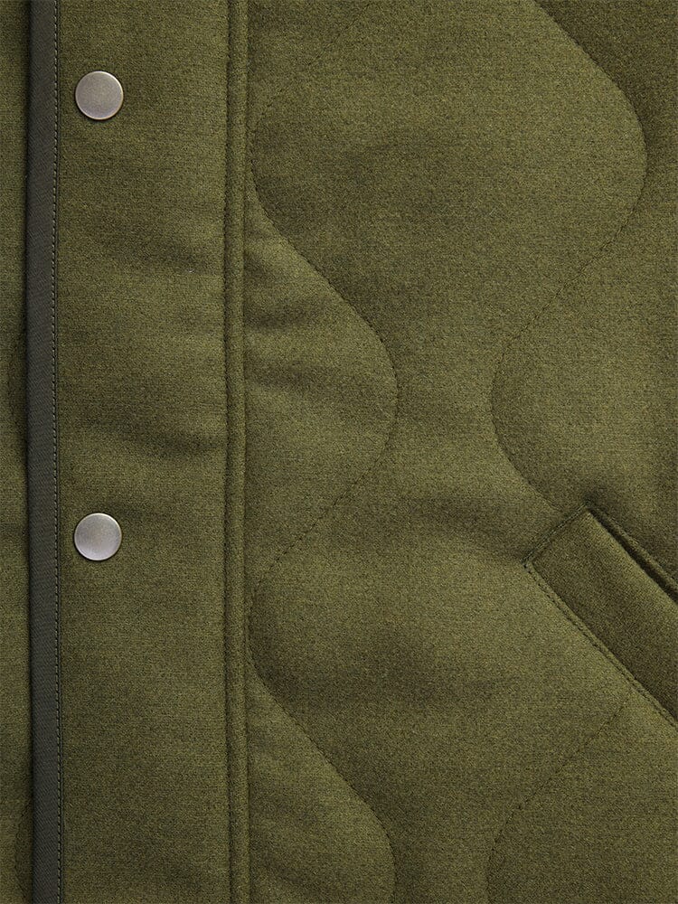 Close-up of the Wool Deck Jacket by Alpha Industries in quilted olive green fabric, featuring a pocket and metal snap buttons.