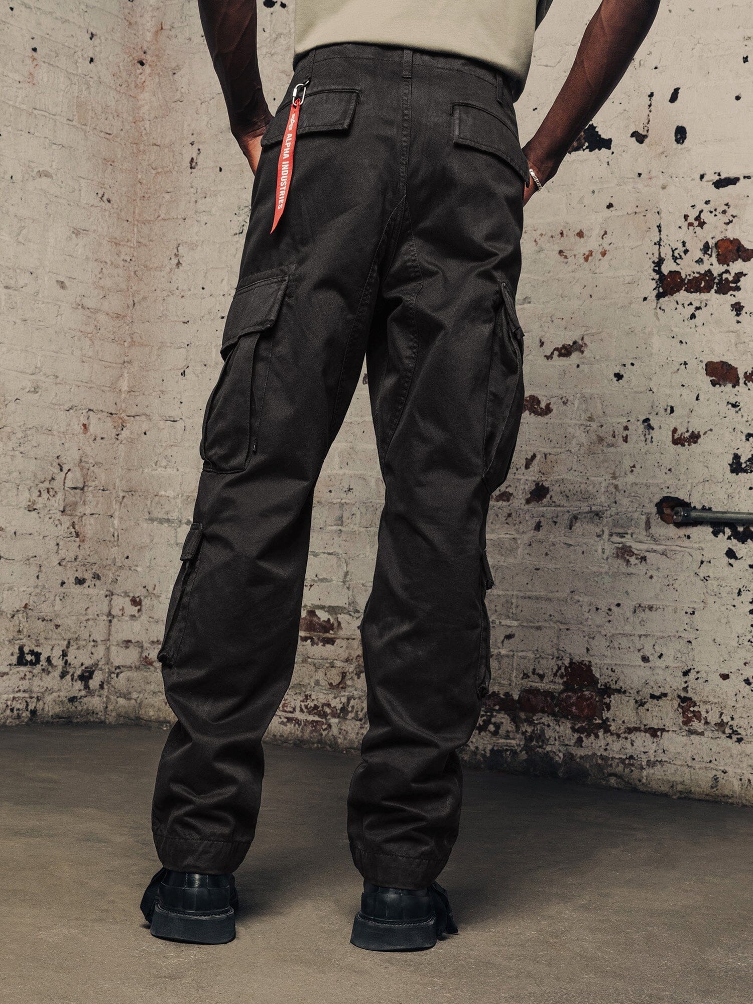 Alpha Industries Acu Pant cargo pants in dark color with multiple pockets, paired with black boots.