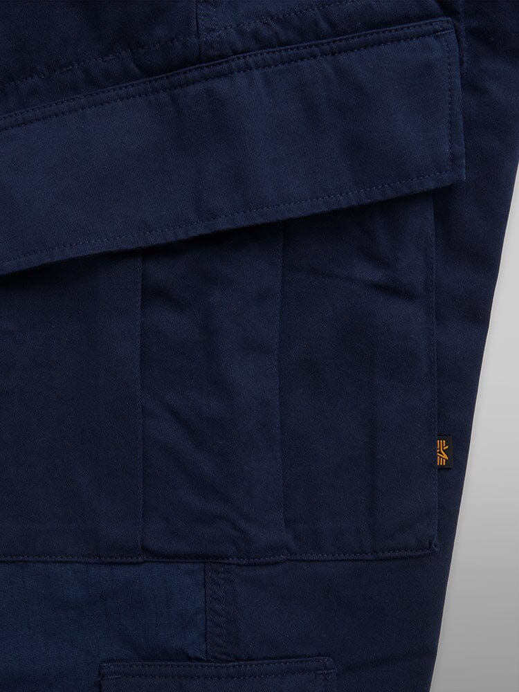 Alpha Industries Acu Pant in navy blue with utility pockets, stitched detailing, and a small orange tag on the right side.