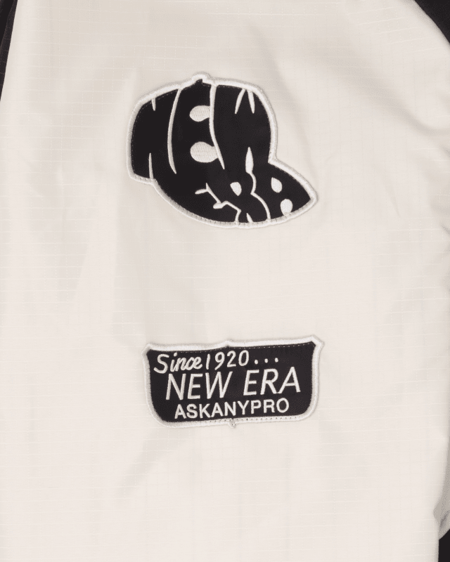 Close-up of the Alpha X New Era L-2B Bomber Jacket by Alpha Industries, highlighting two patches: a stylized New Era logo and a "Since 1920... New Era Ask Any Pro" text patch.