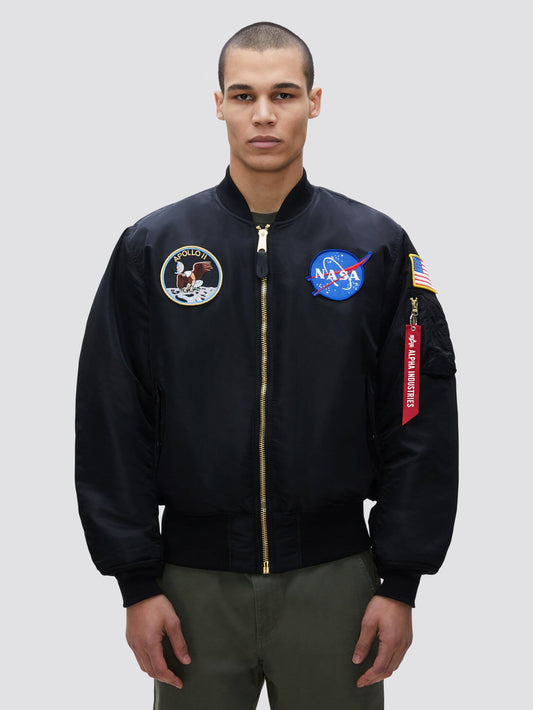 Alpha Industries / NASA Apollo MA-1 Bomber Jacket in Black, with NASA patches, Apollo 11 insignia, American flag, and red Remove Before Flight tag on sleeve.