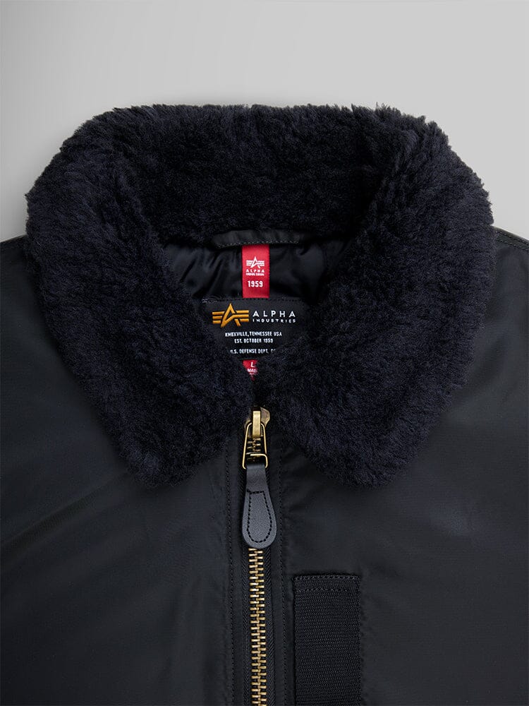 Alpha Industries B-15 Mod Bomber Jacket, black, faux mouton collar, gold zipper, visible brand label inside collar.