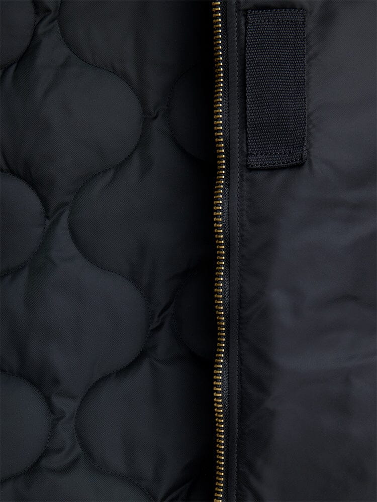 Alpha Industries B-15 Mod Bomber Jacket with black quilted fabric, gold vertical zipper, and black rectangular patch.