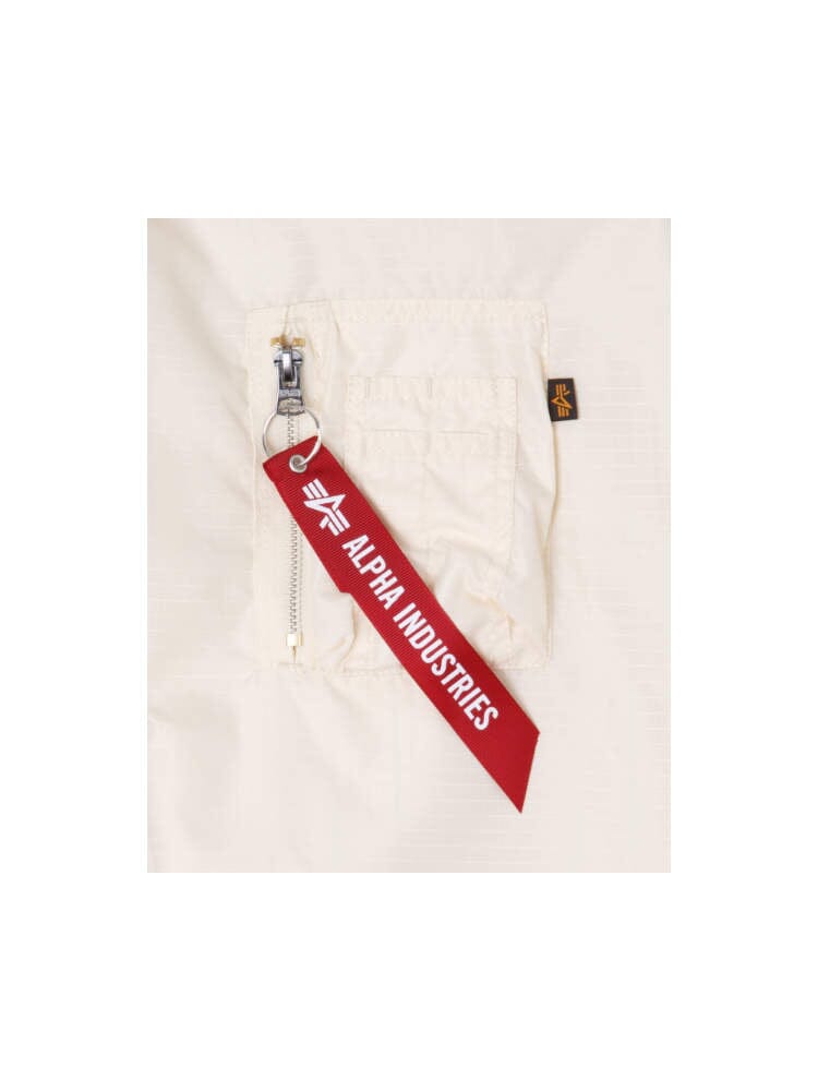 A close-up of the zip pocket on a white Brooklyn Nets x Alpha x New Era L-2B Bomber Jacket showcases a red tag with Alpha Industries branding, offering a glimpse of its pinstripe interior.